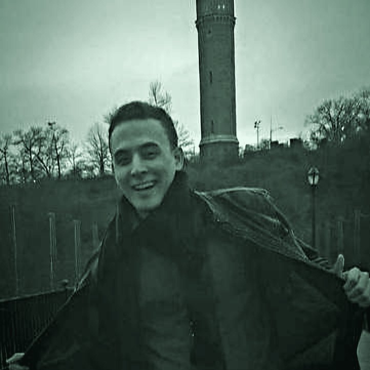 Rafael Mateo sonriendo al aire libre con una chaqueta, con una torre detrás